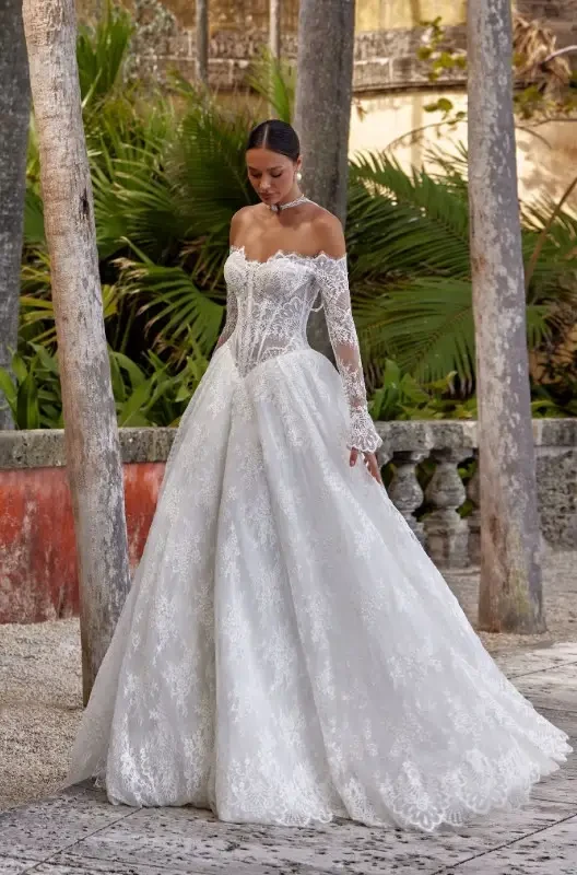 Oksana Mukha - Isolde Wedding Gown featuring all-over lace, a sweetheart neckline, off the shoulder lace long sleeves, and a Basque waist.