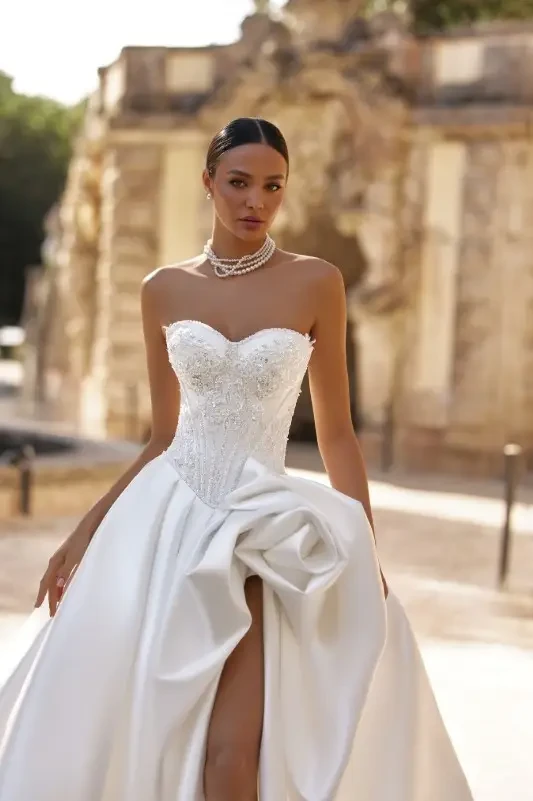 Oksana Mukha Ornella Wedding Gown - A strapless sweetheart with a embroidered, sequined, beaded bodice with exposed boning. The skirt is pleated Mikado with double layered construction and dramatic slit.